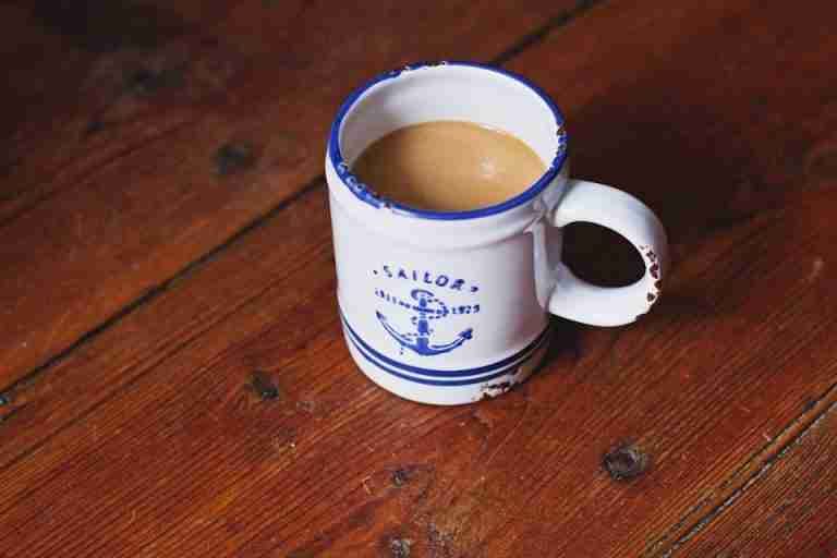 Vintage sailor-themed coffee mug filled with hot brew on a rustic wooden table, evoking a warm and cozy feeling.