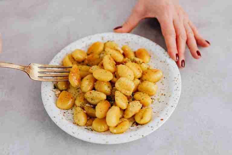 Freshly prepared gnocchi served on a ceramic plate with a fork. Perfect for Italian food lovers.