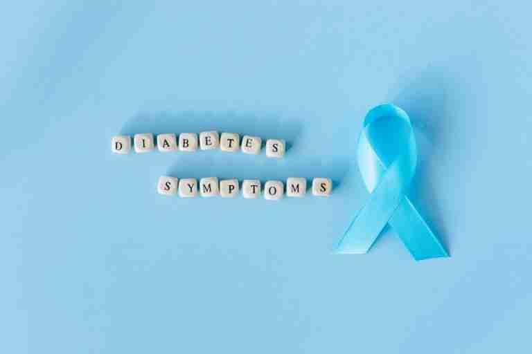 Conceptual image emphasizing diabetes symptoms with a blue awareness ribbon and letter dice.