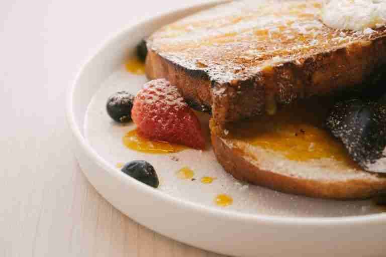 French toast served with berries and syrup on a white plate, perfect for breakfast or brunch.
