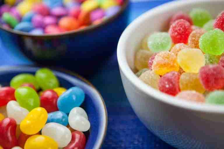 Vibrant assortment of colorful jelly beans and sugar-coated gumdrops in decorative bowls. Perfect for sweet-themed designs.