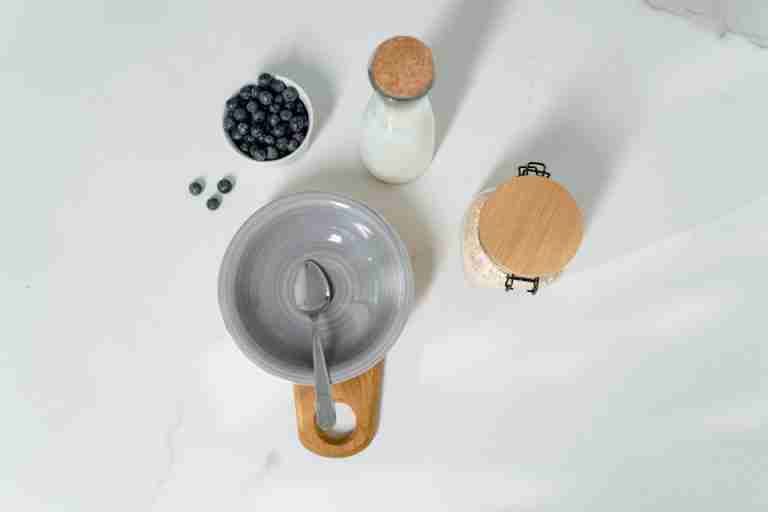 Top view of a healthy breakfast setup with milk, blueberries, and oats.