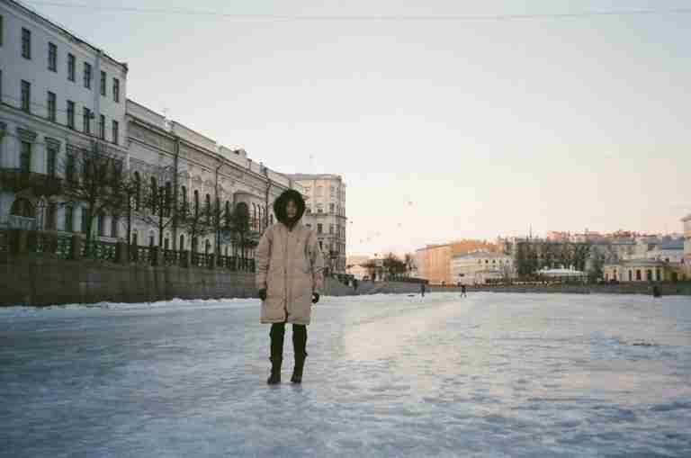 A lone person walks on snow-covered street in a historic city's winter setting.