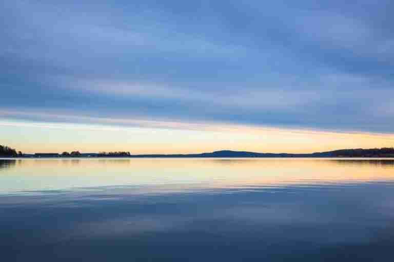 Peaceful sunrise over calm waters in Horten, Norway, reflecting the vibrant sky.