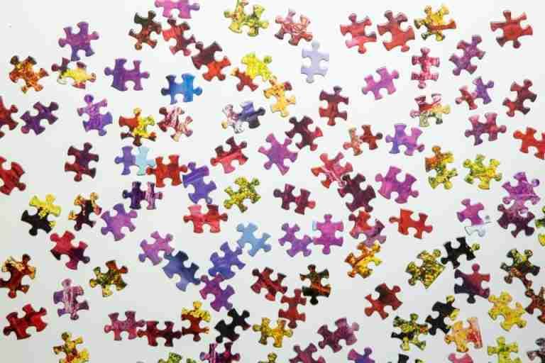 A vibrant collection of jigsaw puzzle pieces scattered randomly on a white surface, showcasing diverse colors and shapes.