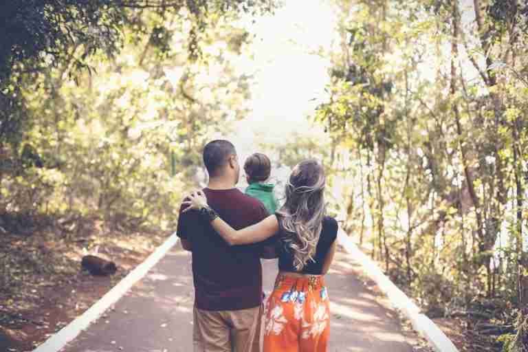 A family enjoying a leisurely walk on a sunny park trail, showcasing togetherness and love.