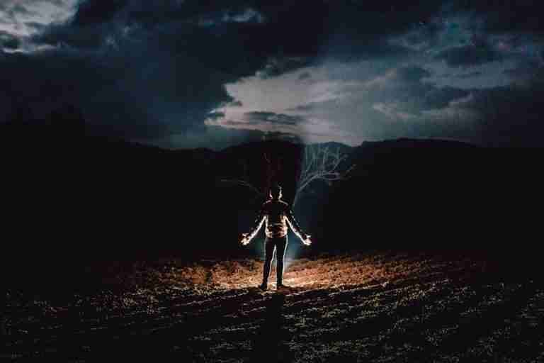 Silhouette of a person illuminated in a night landscape, creating a dramatic and mysterious scene.
