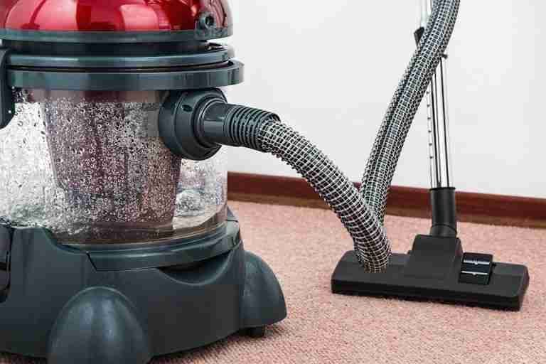 Close-up of a modern vacuum cleaner with water filtration on carpet floor indoors.