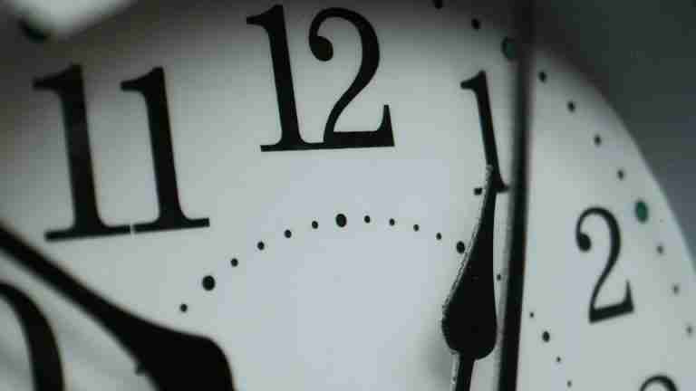 Macro photograph of a clock face showing numbers and minute markers.