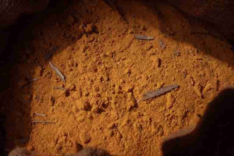 Detailed image of ground turmeric spice in a burlap sack with natural lighting.