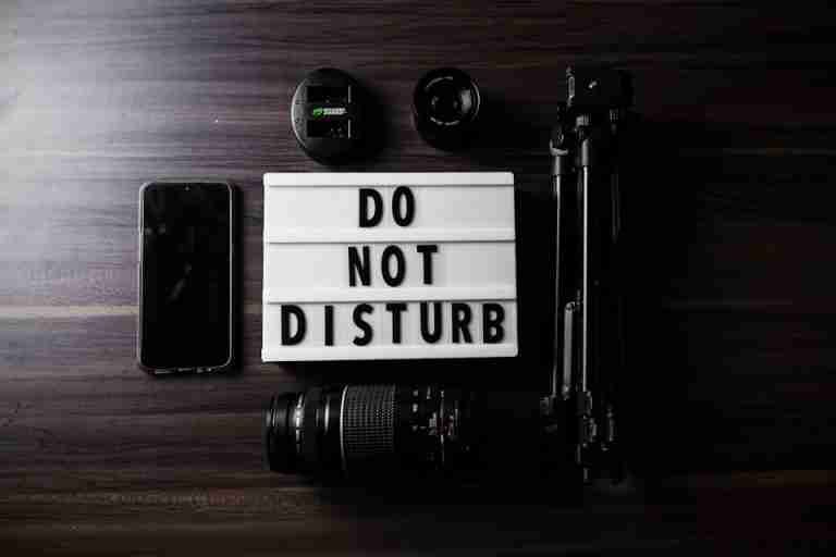 Flat lay of photography gear and a do not disturb sign on a table.