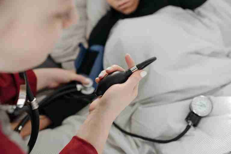 A healthcare professional uses a sphygmomanometer to check a patient's blood pressure at home.