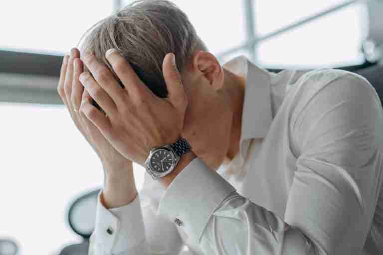 A business professional showing stress and fatigue with head in hands.