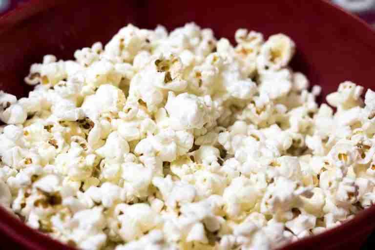 Delicious close-up of freshly popped popcorn in a red bowl, perfect for snacking.