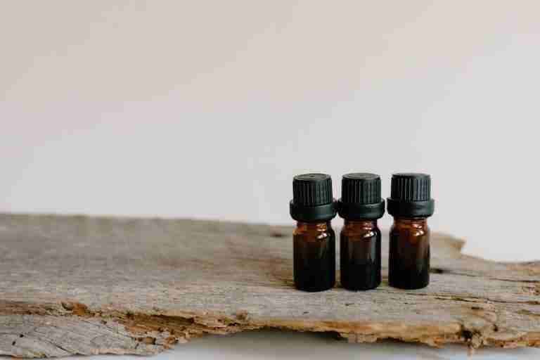 Three essential oil bottles on rustic wood surface, perfect for aromatherapy and natural healing themes.