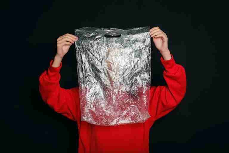 Conceptual image of a person holding a clear plastic bag, symbolizing pollution and recycling themes.