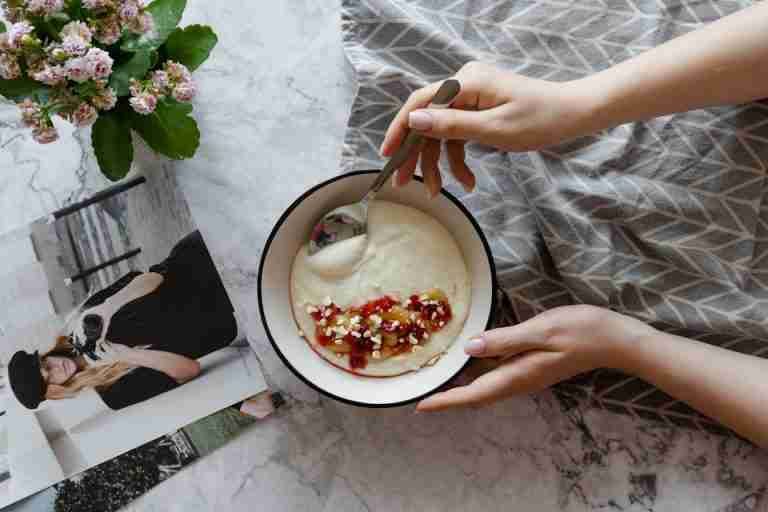 A warm breakfast setup featuring a bowl of porridge with fruit and nuts, perfect for a cozy morning.