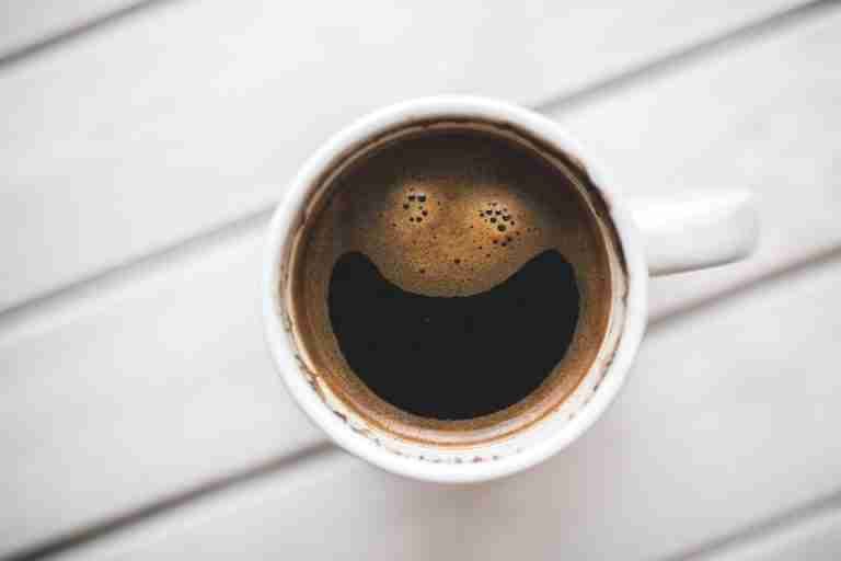 A coffee cup with a smiling face pattern on a wooden table, perfect for morning routines.