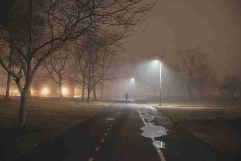 A solitary walk on a misty winter morning in Stamford, Connecticut, with streetlights reflecting on wet paths.