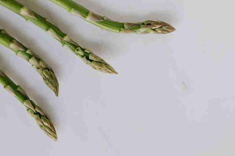 Close-up of fresh asparagus tips on a white background, highlighting freshness and healthy eating.