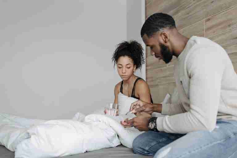 A couple in a bedroom caring for each other during illness. Support and empathy in a home setting.