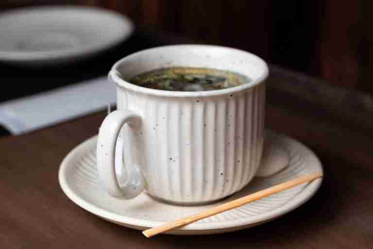 A close-up of a ceramic teacup filled with chamomile tea on a wooden table in São Paulo.
