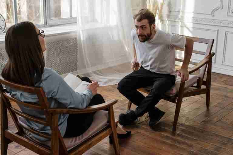 A therapist engages with a male patient in a counseling session.