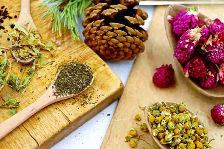 A vibrant assortment of dry herbs and flowers for artisan tea making on rustic wooden boards.