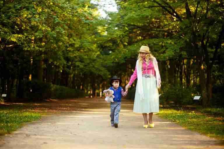 A cheerful mother and son enjoy a walk in a sunlit park, embracing nature and togetherness.