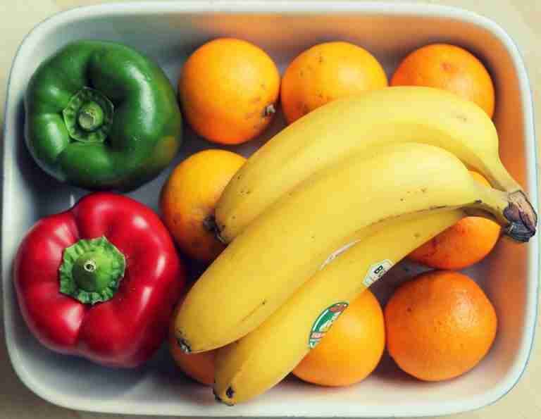 Vibrant mix of fruits and vegetables, including bananas and peppers, in a bowl.