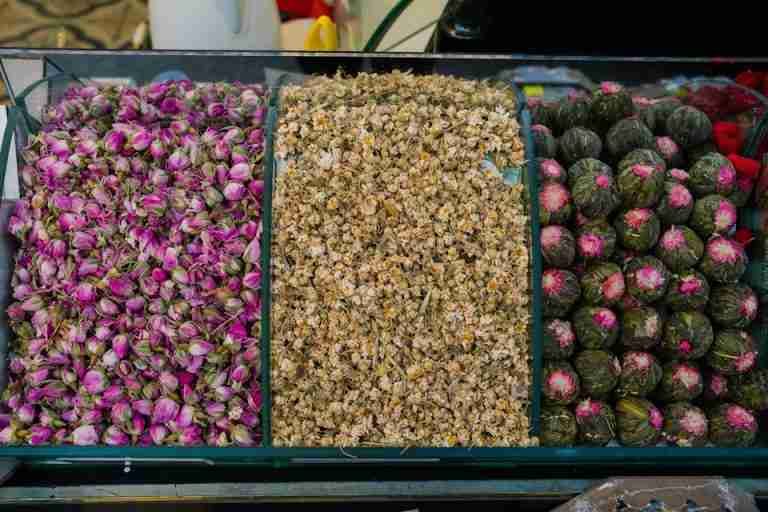Top view of assorted dried flowers including rosebuds, chamomile, and blooming teas for herbal blends.