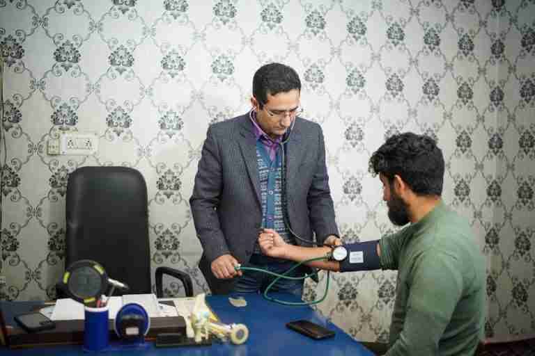 Doctor checking patient's blood pressure during medical consultation indoors.