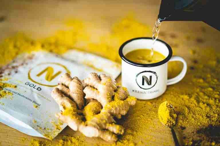 Pouring hot water into a mug with ginger and mushroom blend for a healthy beverage.