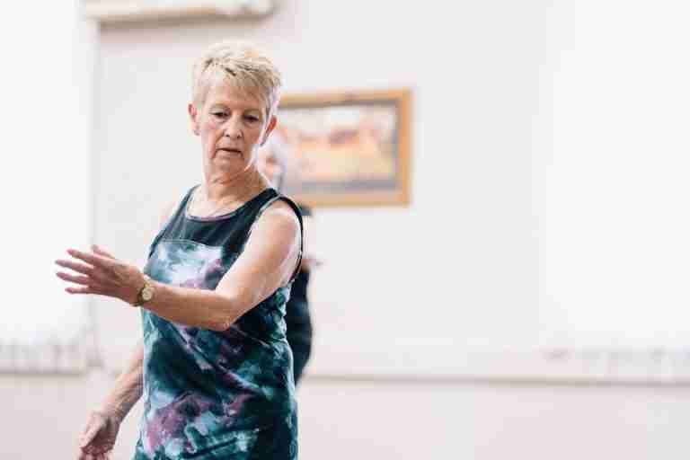 Elderly woman performing dance exercises indoors, focused and graceful.