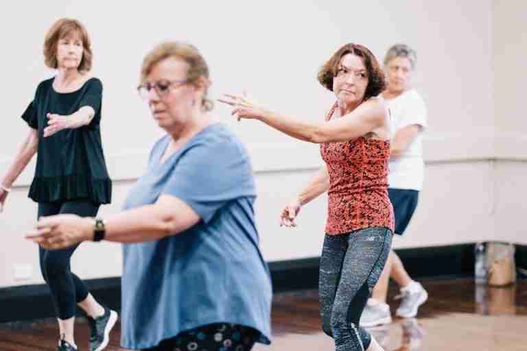 Senior women enjoying a group dance exercise in a fitness class, promoting health and togetherness.