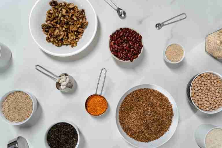 Flat lay of nuts, grains, and beans artfully arranged on a marble countertop.