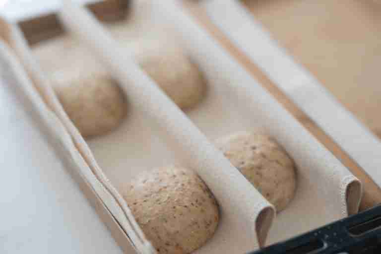 Close-up of artisanal sourdough bread dough proofing in a wooden box, ready for baking.