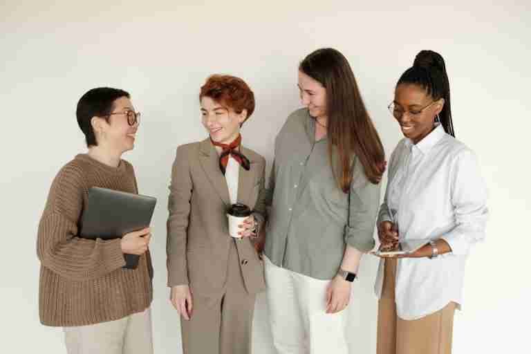 A diverse group of women coworkers smiling together in a professional office setting.