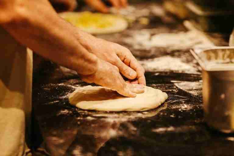 Close-up of hands artfully kneading dough on a flour-dusted surface, highlighting the handmade process.