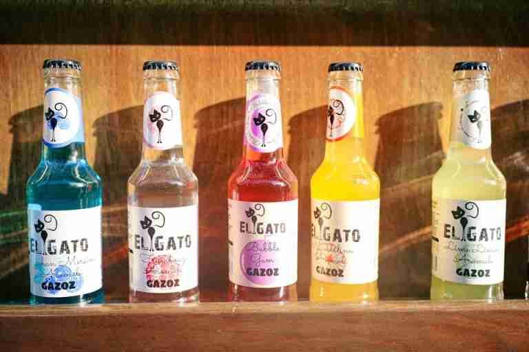 Vibrant El Gato soda bottles arranged in sunlight, showcasing unique flavors.