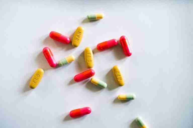 Colorful capsules and tablets scattered on a white surface, showcasing variety in medicines.