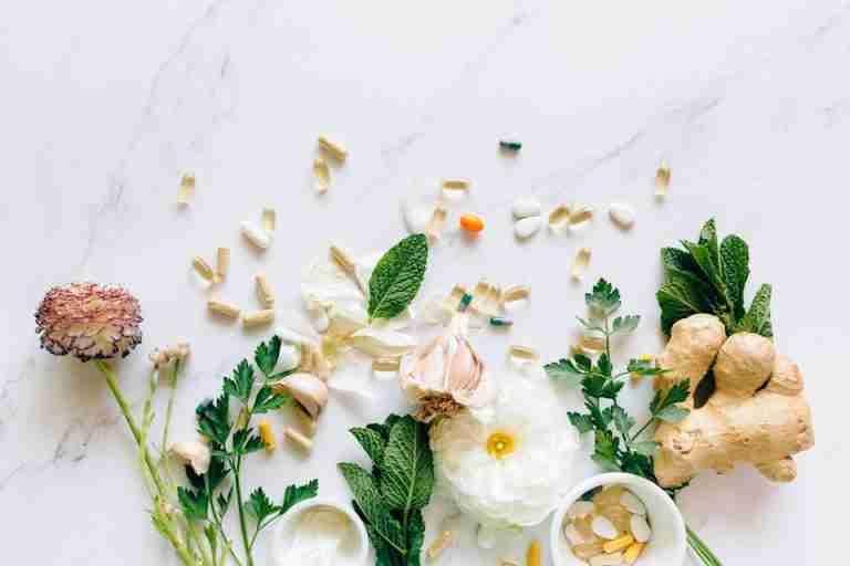 Natural herbs and pills arranged on a marble surface for a holistic healthcare theme.
