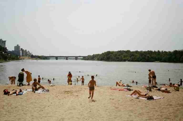 People relaxing on a sandy beach by the Dnieper River in Kyiv during summer.