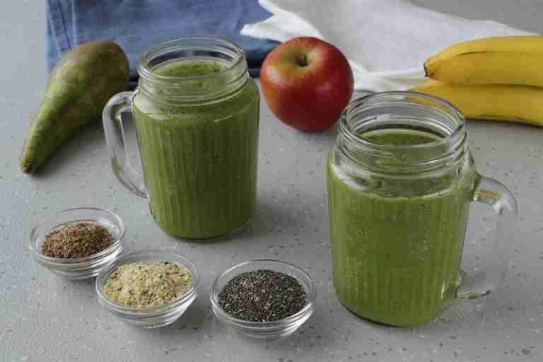 A nutritious green smoothie with apple, pear, and seeds in a cozy kitchen setting.