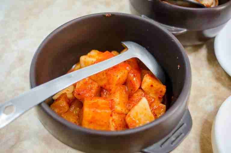 Close-up of homemade spicy kimchi in a ceramic bowl, showcasing vibrant flavors.