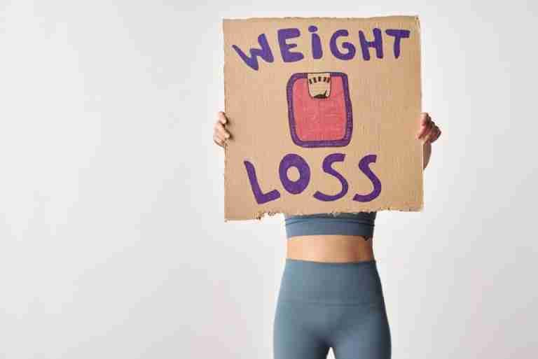 Person holding 'weight loss' sign for fitness motivation and health goals.