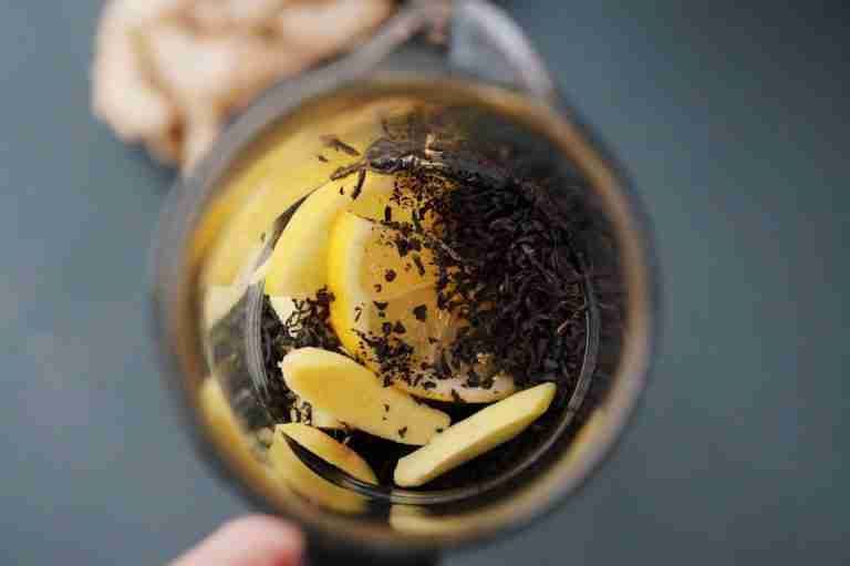 A fresh lemon and ginger tea infusion seen from above in a glass teapot.