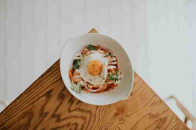 A beautifully plated Korean dish with kimchi and a fried egg on a wooden table, perfect for lunch or dinner.
