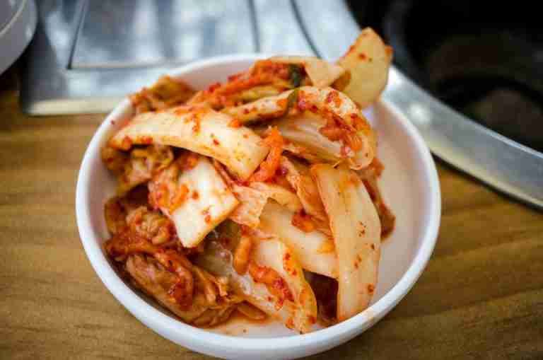 Close-up of spicy Korean kimchi in a white ceramic bowl, perfect for food enthusiasts.