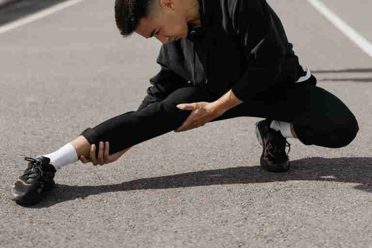 A young man performs stretching exercises on a city street, focusing on flexibility and fitness.